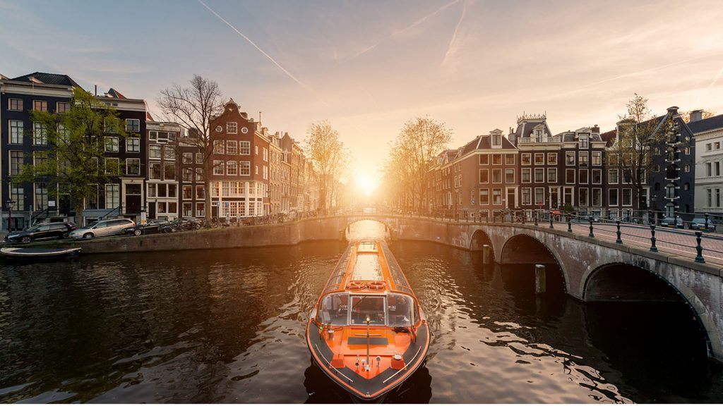 Sunset in Amsterdam as boat takes people on a canal cruise