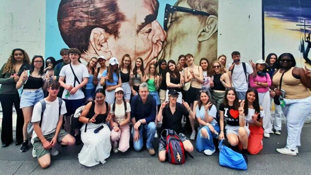 School group on a History Tour posing for a photo at the East Side Gallery in Berlin