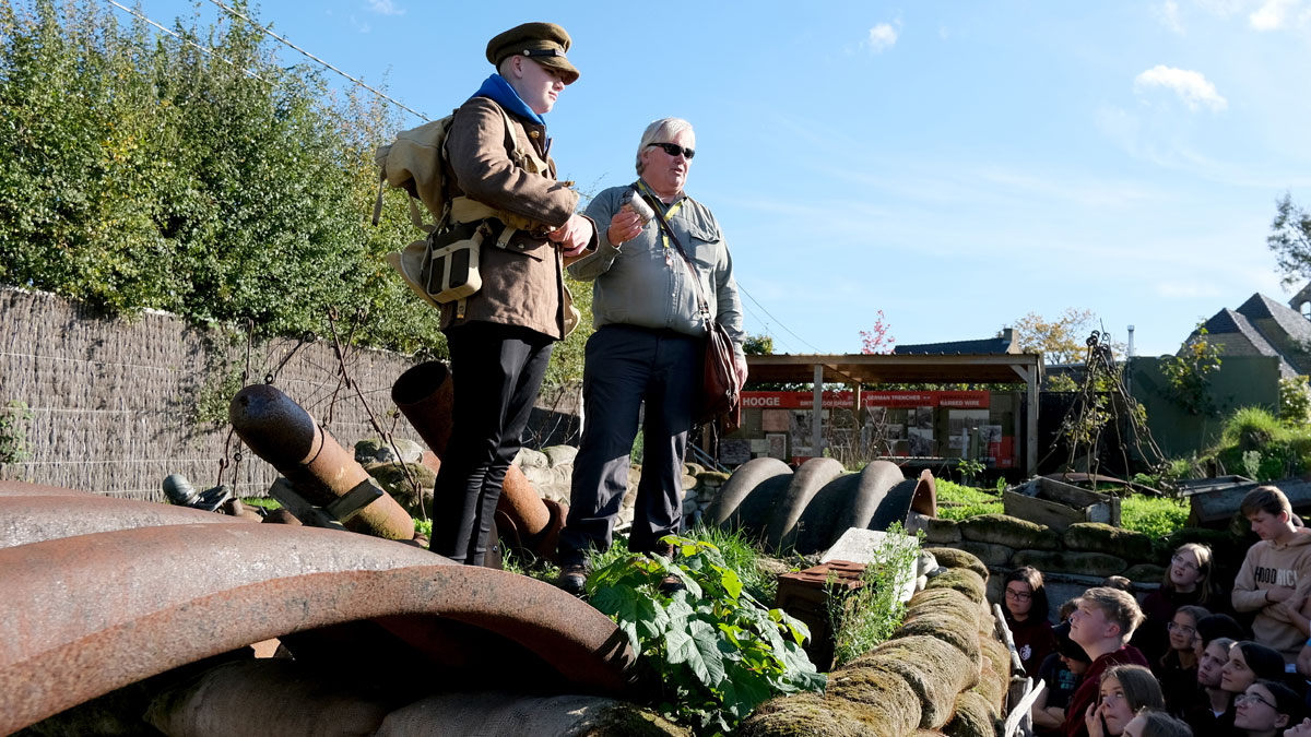 History Tour Guide, Richard Broadhead, presents with a student dressed up in clothing from the World War to other students at the Hooge Crater.