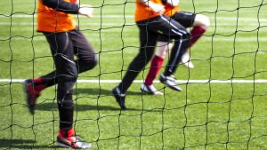 Legs of young players warming up on a grass football pitch