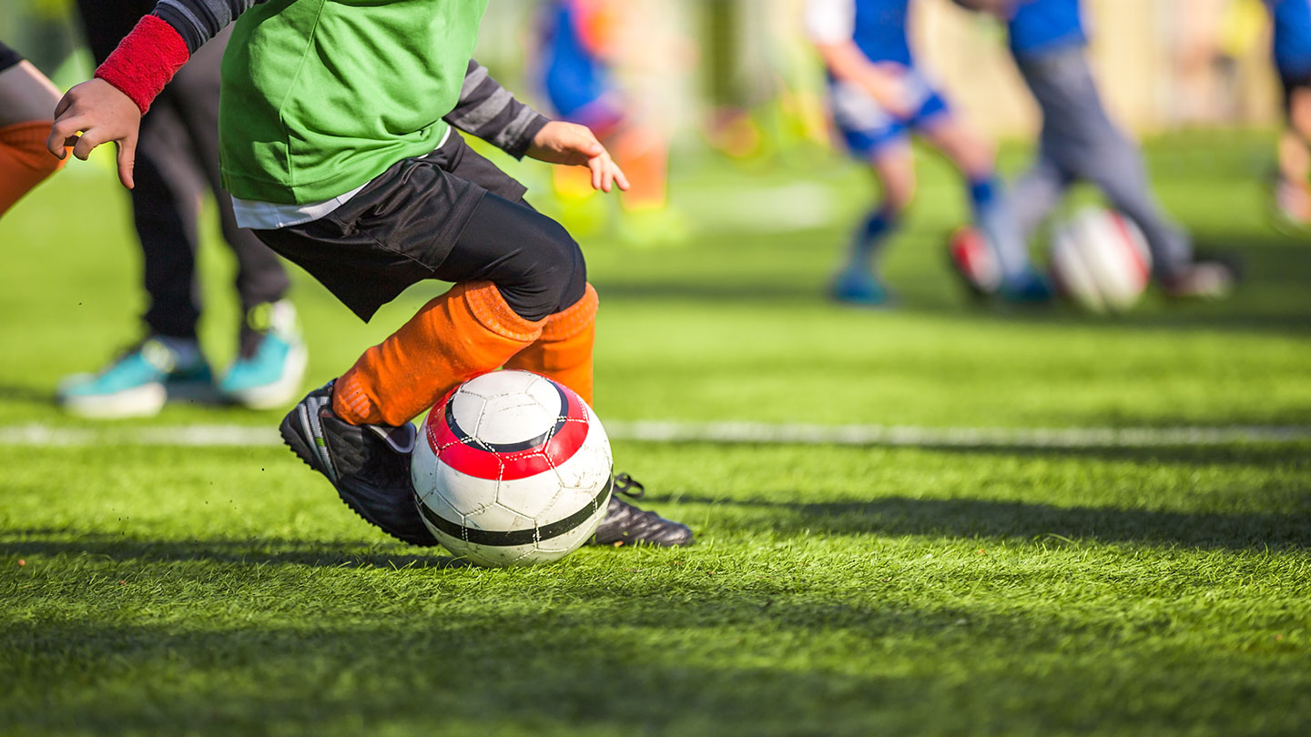 Young players legs controlling the football on a grass pitch