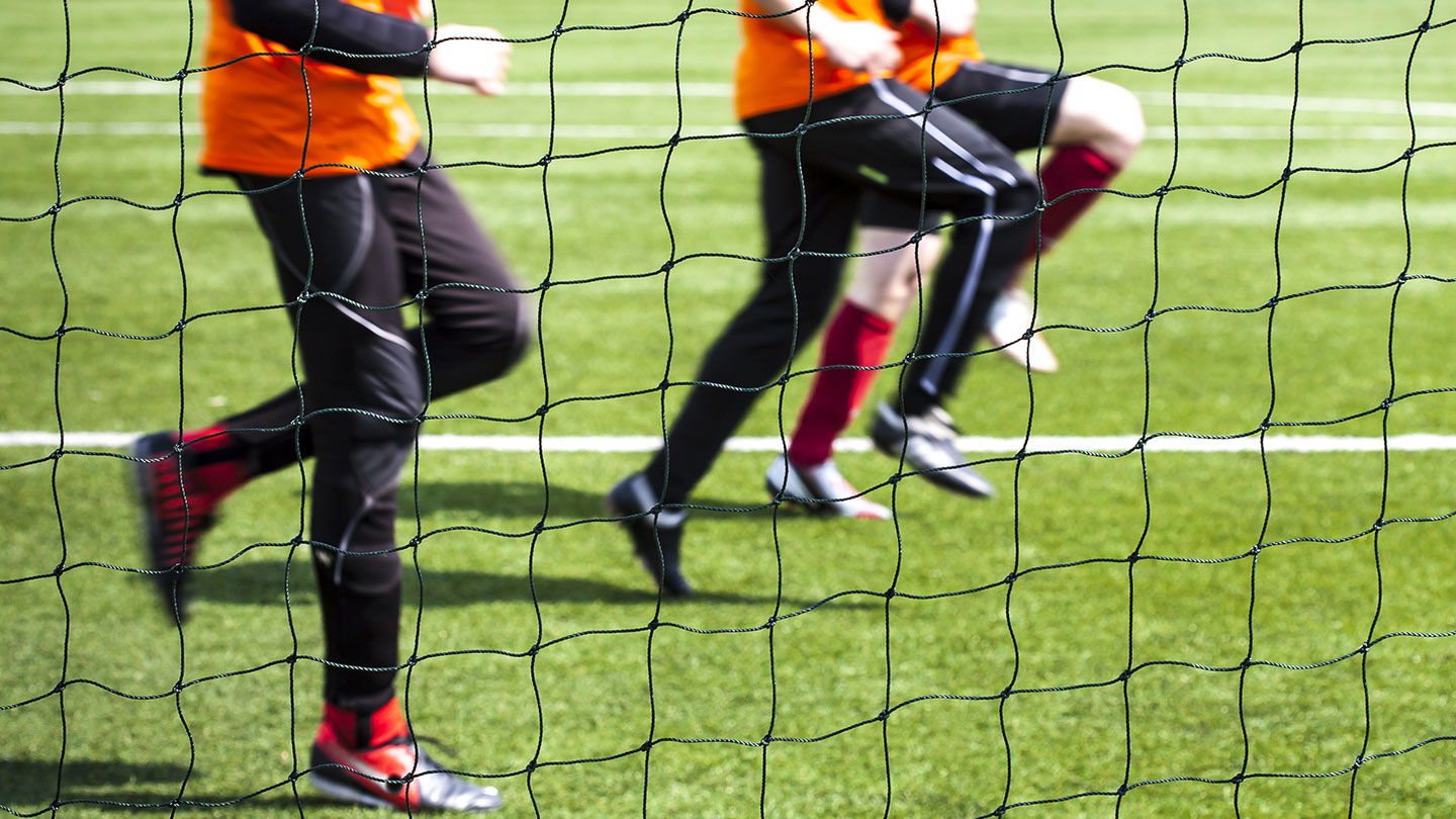 Legs of young players warming up on a grass football pitch