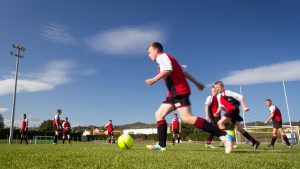 Boy playing football under blue skies.