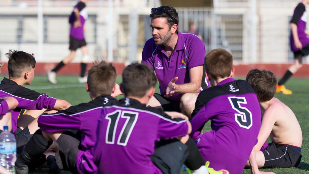 Coach talking to his football team wearing purple kit