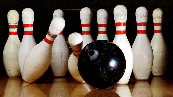 Bowling bowl with bowling pins being knocked over.