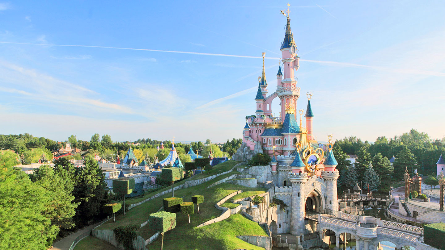 DisDisneyland® Paris Castle with a background of blue ski and greenery