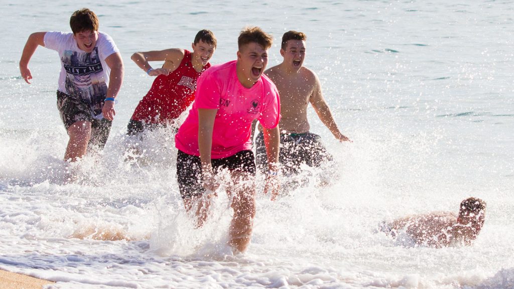 Teenagers playing and running in the sea