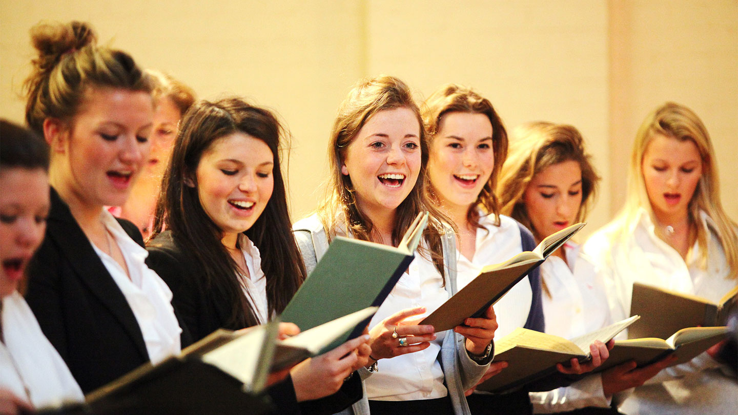 10 Best Ways on How To Prepare for Your Music Tour: A woman choir sing with songbooks in hand
