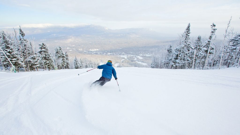 Skiier in a blue jacket heading down slope at Sugarloaf