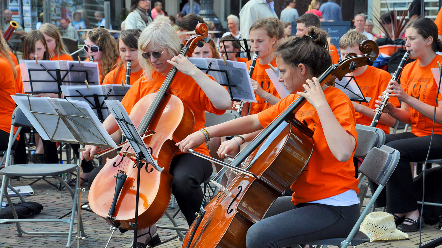 10 Best Ways on How To Prepare for Your Music Tour: a multi-instrument band perform in orange t-shirts outside