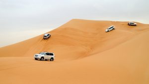 Three jeeps riding the Sahara sand dunes in Dubai.
