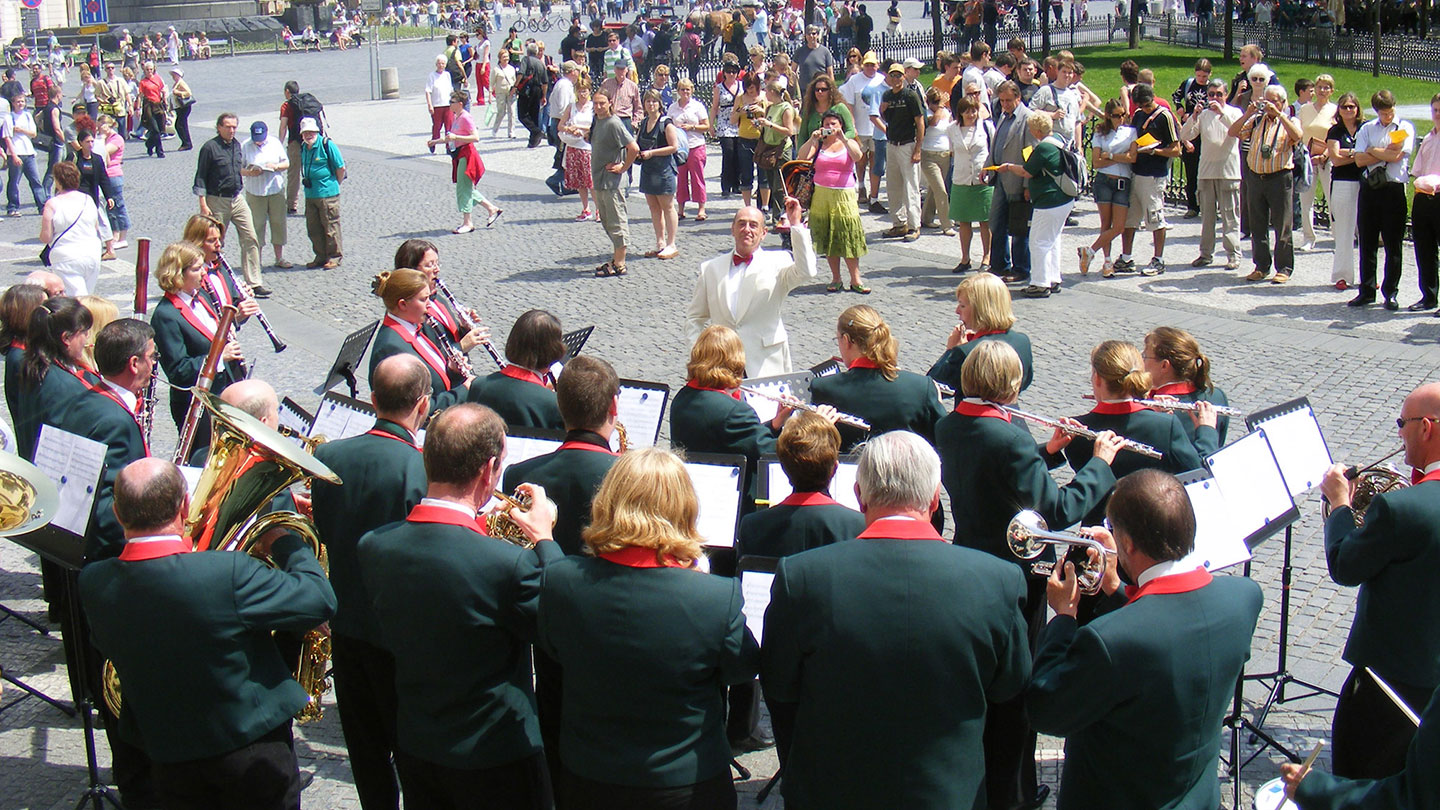 10 Best Ways on How To Prepare for Your Music Tour: a band perform outside with their conductor in front of them
