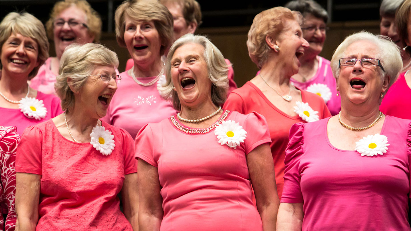 A group of older ladies in pink laugh together and knowing your group needs is 1 of 10 Best Ways on How To Prepare for Your Music Tour