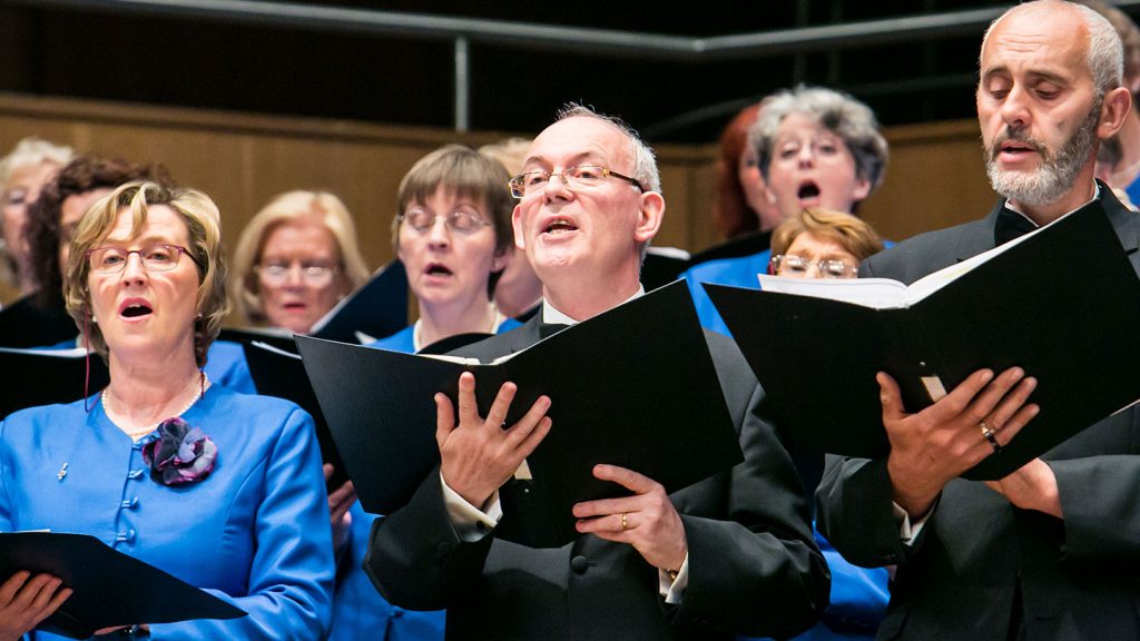 An adult choir performing on a stage together