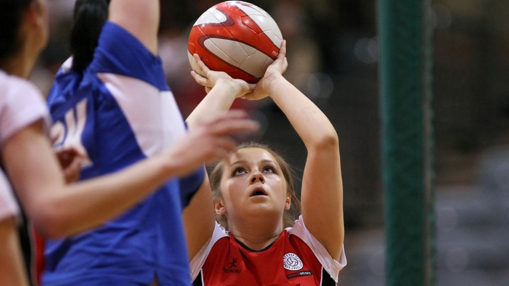 A girl netball player prepares to shoot.