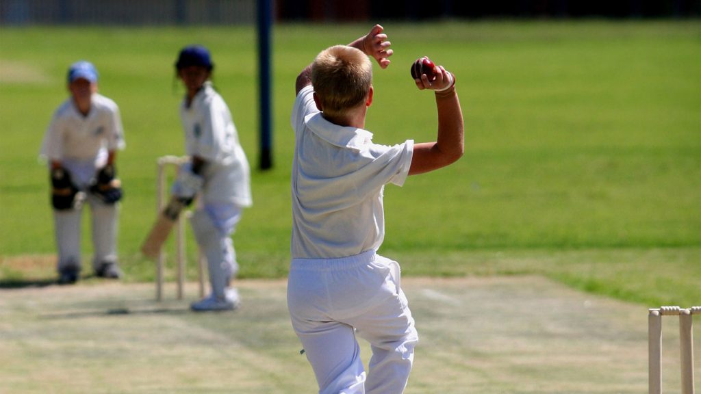 Young boys bowls against an opposing batsman.