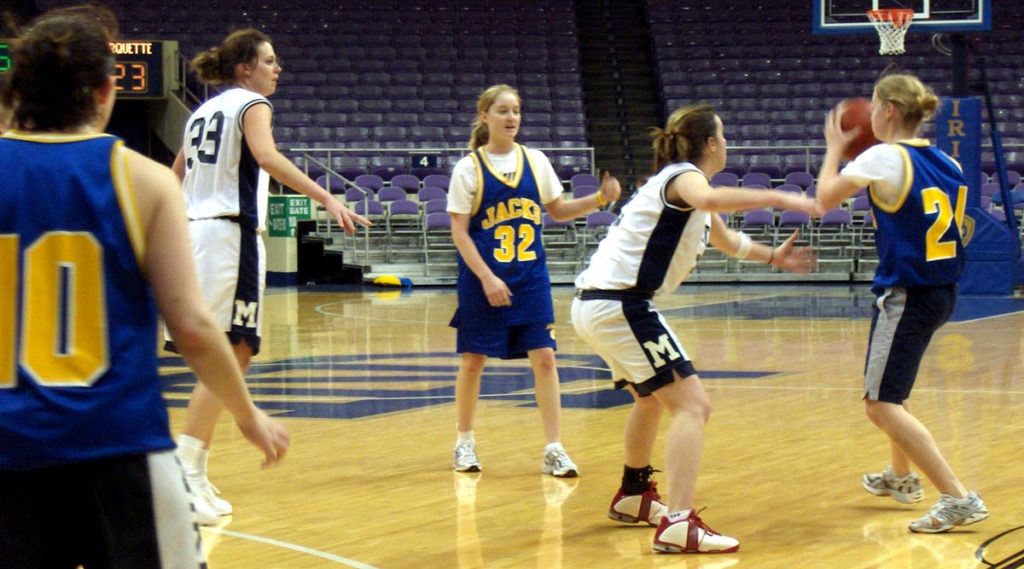 Girl basketball players compete for the ball in an inside court
