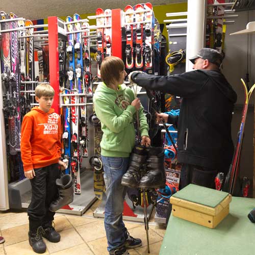 two skiers are helped out by the ski and snowboard gear shop worker