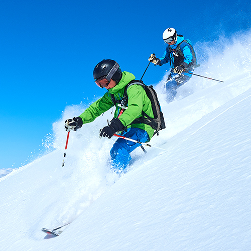 How To Pick The Perfect School Ski Resort: two skiers skiing though snow powder