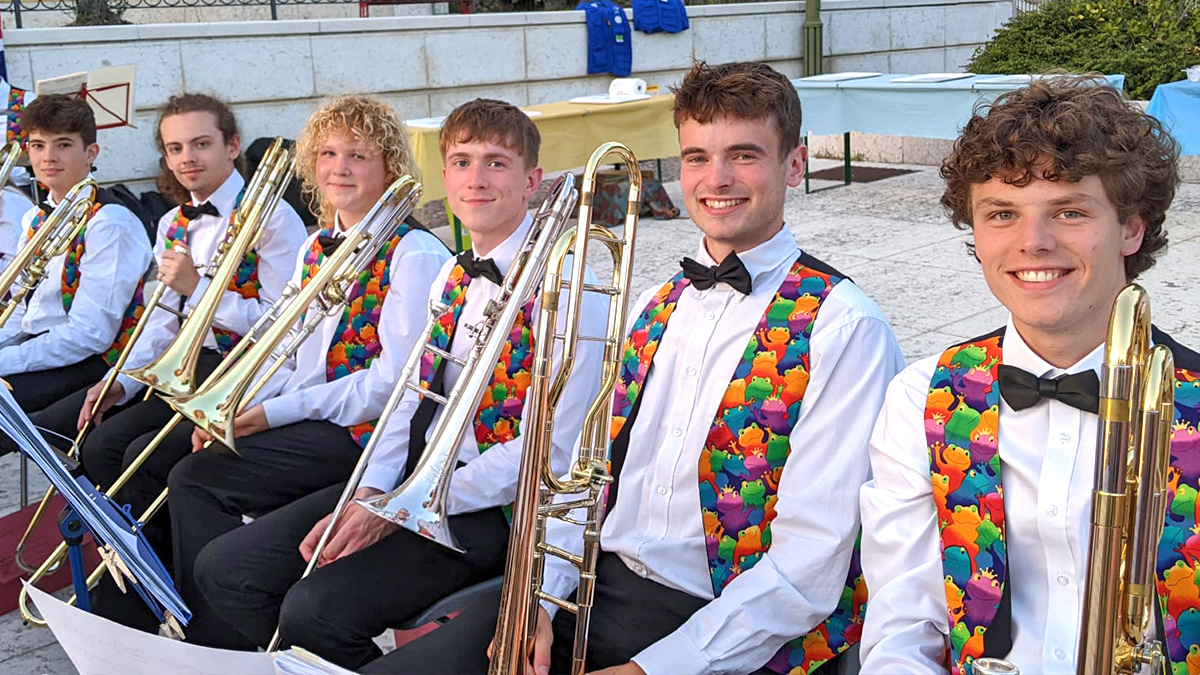 10 Best Ways on How To Prepare for Your Music Tour: Trombone line of youth tour smile in multi-coloured waistcoats