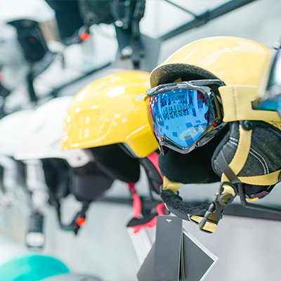 School Skiing in Andorra and Everything You Need To Know: Ski and snowboard helmets and goggles on a display rack inside a shop