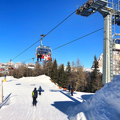 School Skiing in Andorra and Everything You Need To Know: People ski on slope beneath a ski lift carrying people up a slope