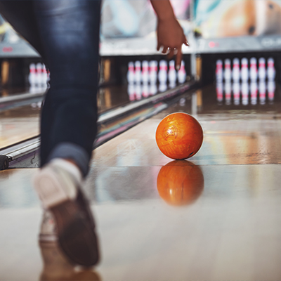 Young person bowling a ball down a bowling alley