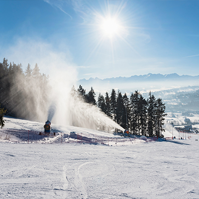 snow cannons blasting snow over a ski slope