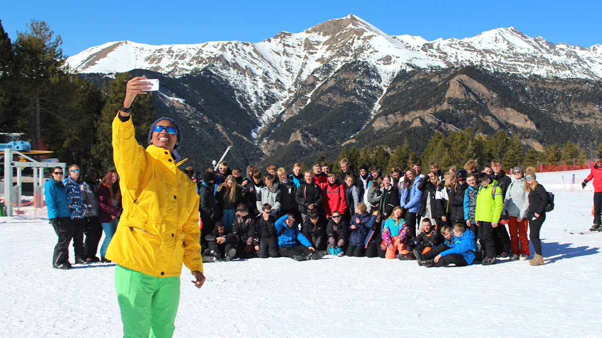 Happy teacher taking a selfie on a ski slope with all of her students