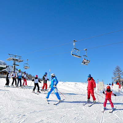 People skiing on a slope with ski lifts above in Sestriere, Italy 3 of 5 School Ski Resorts Great For Easter Skiing