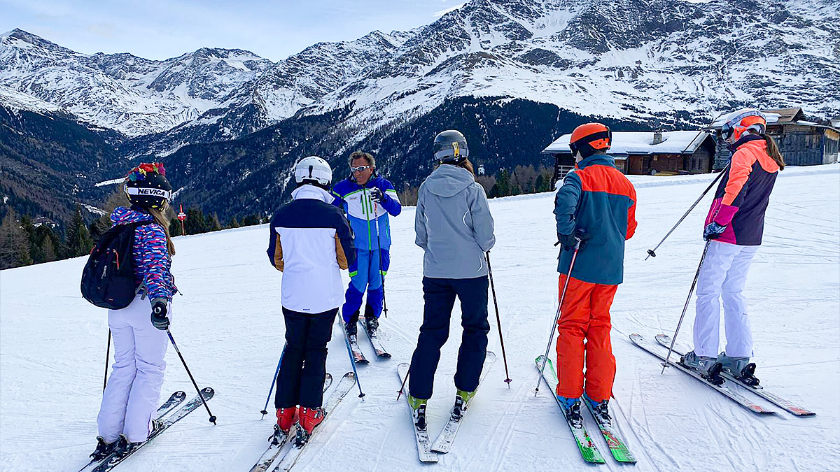 5 students with a ski instructor on ski's with a mountain landscape in Bormio ski resort