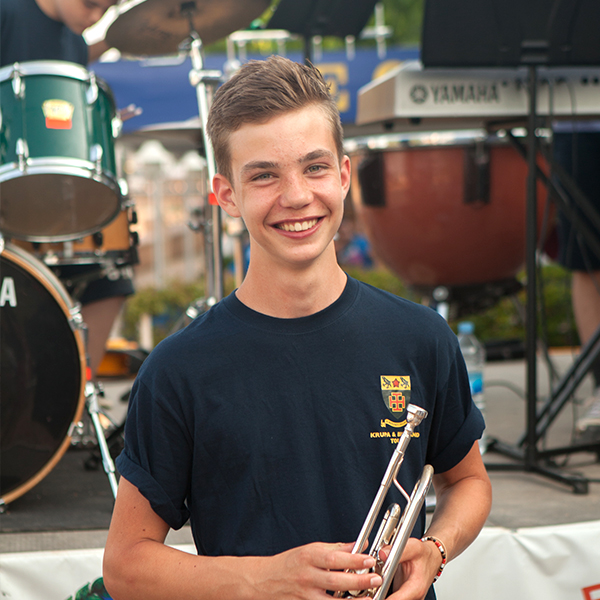 Boy smiles with instrument in hand in image on blog 4 Reasons and 4 Affordable Tips for Your School Tour 
