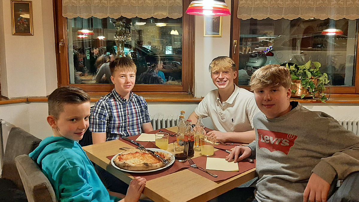 4 young students enjoying fresh pizzas at a restaurant in the slopes of Tarvisio, Italy in the February half-term ski season 2023