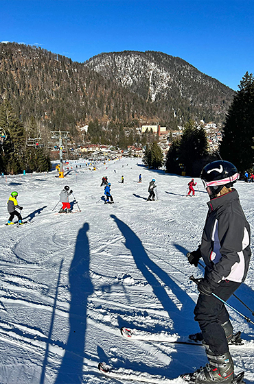Young skiers enjoying the sunny slopes in Tarvisio, Italy in the February half-term ski season 2023