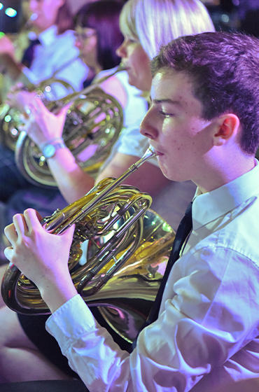 A youth band member playing the French horn on a Rayburn Tours concert tour