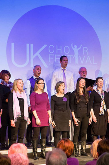 People performing on the stage of the UK Choir Festival