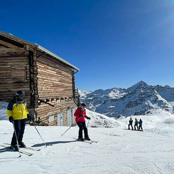 A handful of skiers, with a log cabin to the left and calmer slopes is 1 of 6 Advantages of Skiing in December