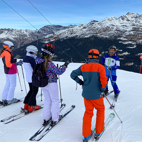 Ski instructors in a class overlooking mountain peaks
