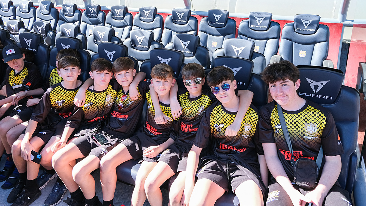 Students pose on the player dug-out seats on a FC Barcelona Nou Camp stadium tour