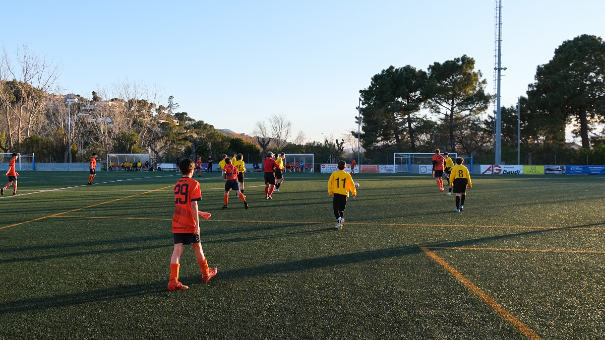 students from a UK Barcelona School Football Tour and their Spanish opposition run towards the ball in a match against each other