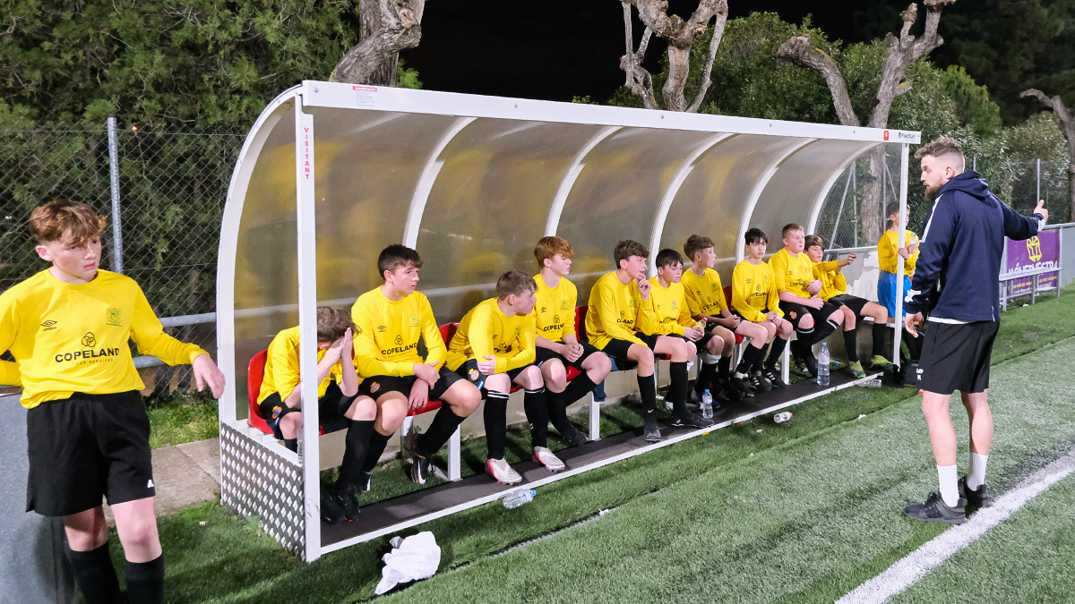 UK school receive instruction from their teacher in the dug-out in their match against a local side on their Barcelona School Football Tour