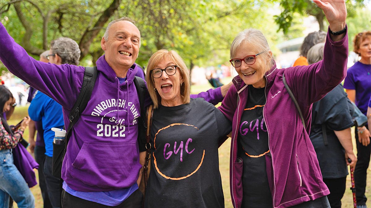 Three music group members pose and smile to the camera outside