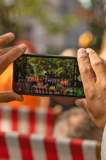 Man filming choir performance using his smartphone whilst sat on a deck chair in sunny Edinburgh - during the Fringe Festival