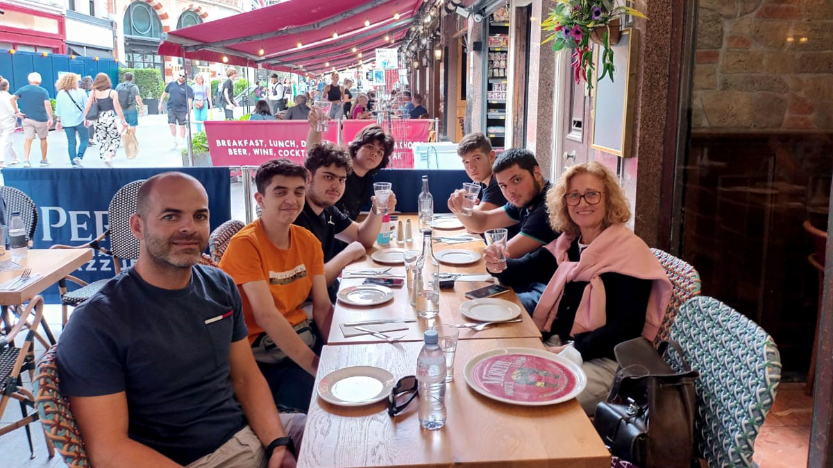 Students and staff sit at a table and pose for a photo.