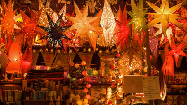 Different coloured Christmas stars hang above a stall in a Christmas market