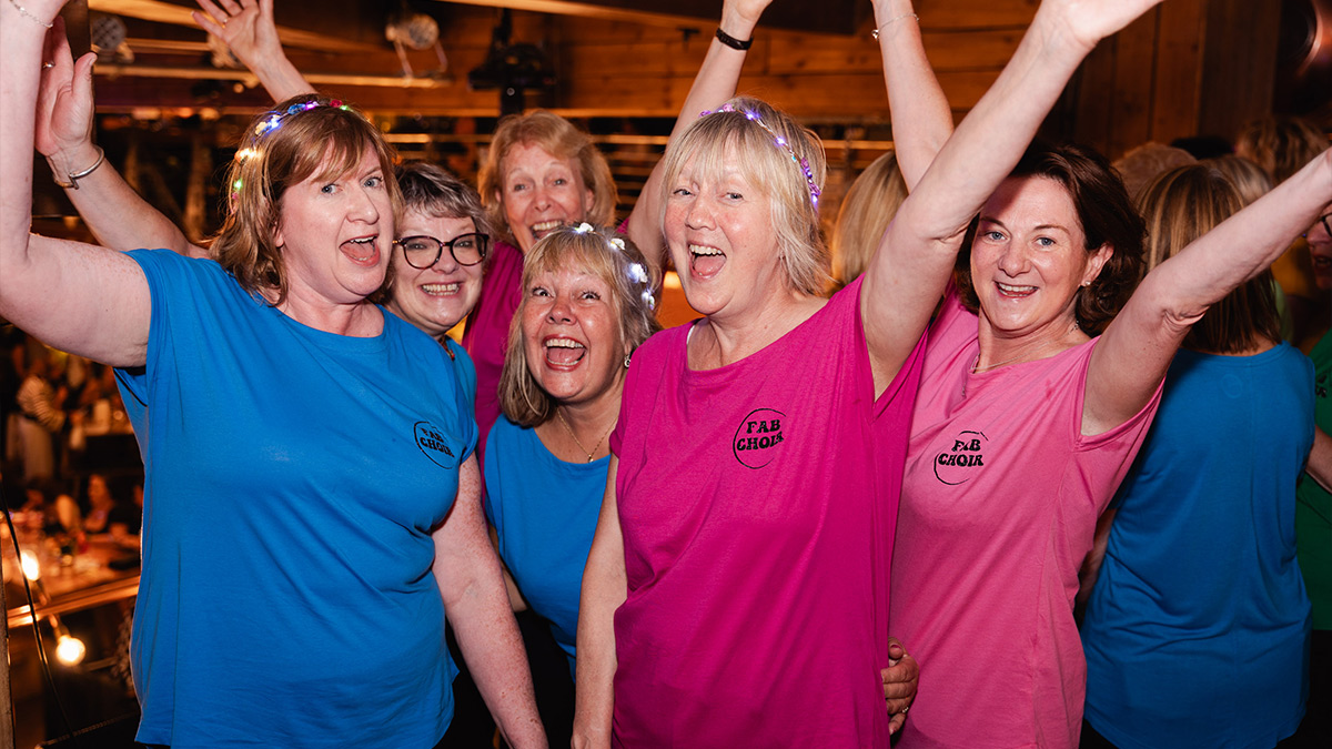 Ladies from Fab Choir cheer, with hands high, in Brewhemia during the Edinburgh Fringe Festival.