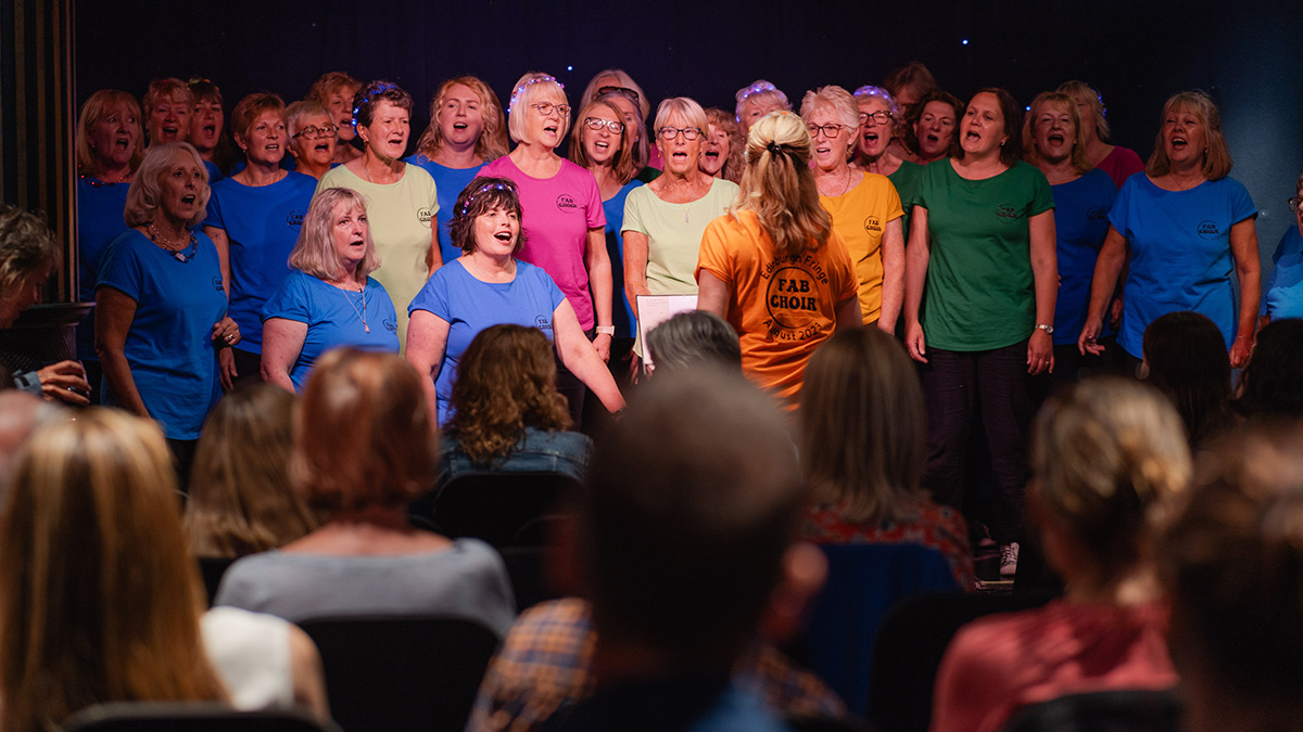 Fab Choir perform at Le Monde in the background with a packed out audience in the foreground.