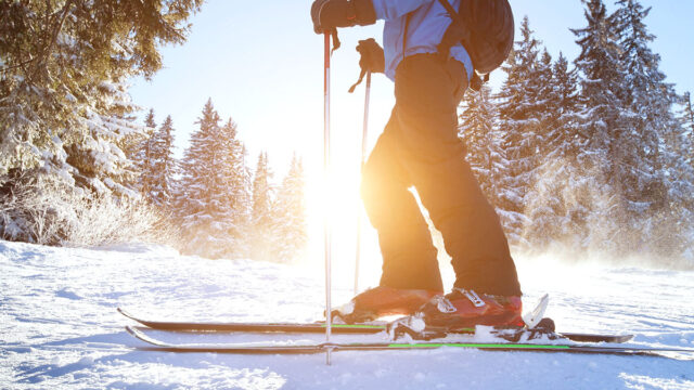 Skier on a slope with the sun rising in the background