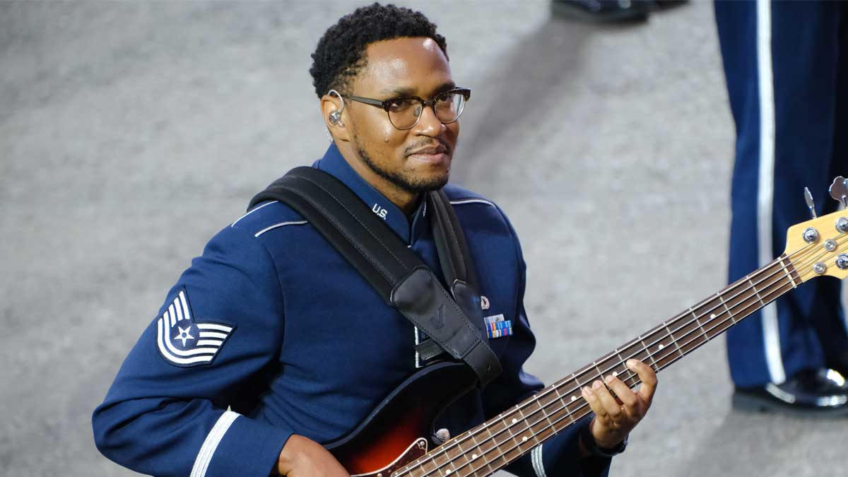 A bassist wearing a navy blue military suit performs at the Edinburgh Tattoo.