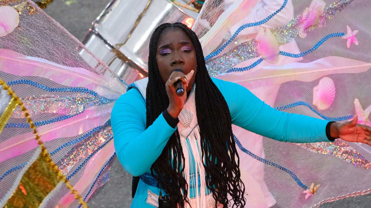 A singer from the Trinidad and Tobago Defence Force Steel Orchestra, wearing light blue and vibrant, colourful pink wings performs at the Edinburgh Tattoo.